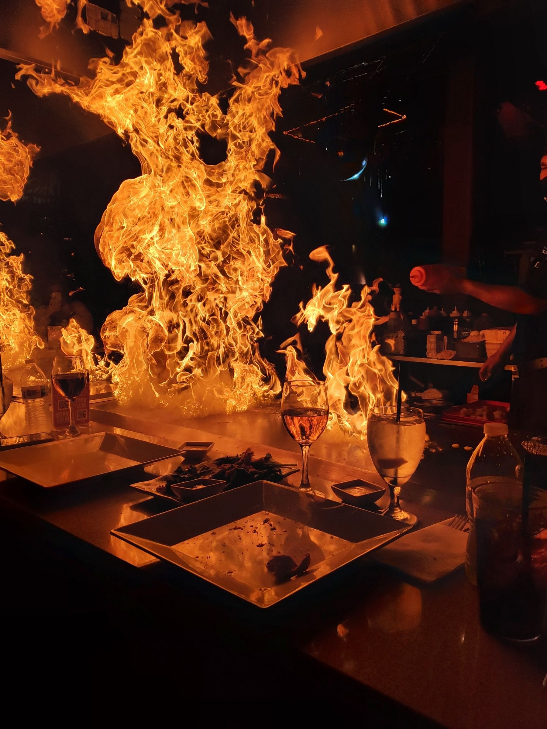 Chef cooking over open flame in a live-fire kitchen